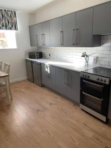 a kitchen with gray cabinets and a stove and a table at Central 3 Bedroom Townhouse in Wick