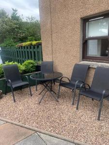 three chairs and a table in front of a building at Central 3 Bedroom Townhouse in Wick