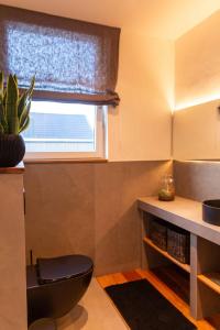 a bathroom with a black toilet and a window at N6Quartier in Bad Münstereifel