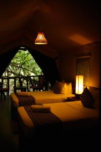 a bedroom with two beds and a light fixture at Athgira River Camping - Udawalawe in Udawalawe