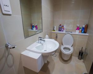 um banheiro com uma pia, um vaso sanitário e um espelho em Luxury Apartment by the Sea with Amazing Amenities at Pearl Qatar em Doha