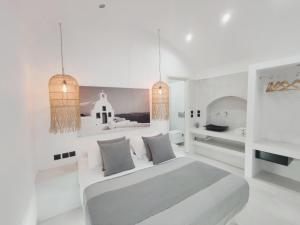 a white bedroom with a bed and two windows at Fira Caldera Suites in Fira