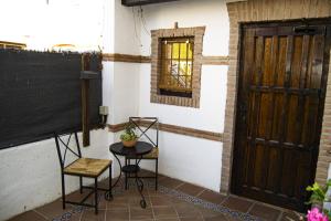 un patio con 2 sillas, una mesa y una puerta en El Librero de La Alhambra, en La Zubia
