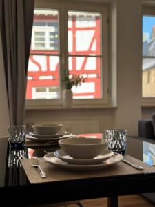 a table with plates and bowls on it with a window at Traumhafte Wohnung am Stadtbrunnen der Altstadt in Pfullendorf