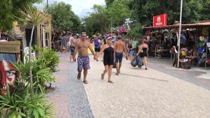 un gruppo di persone che camminano lungo una strada di Ytamãní l apartamentos a Santa Cruz Cabrália