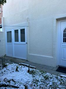 un edificio blanco con una puerta y nieve en el suelo en Studio cosy avec mezzanine, en La Verrière
