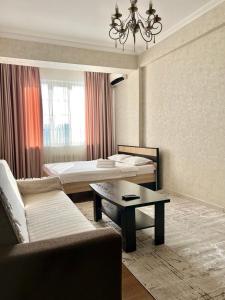 um quarto de hotel com duas camas e um sofá e uma mesa em PROMENADE BISHKEK em Bishkek
