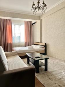 a hotel room with two beds and a couch and a table at PROMENADE BISHKEK in Bishkek
