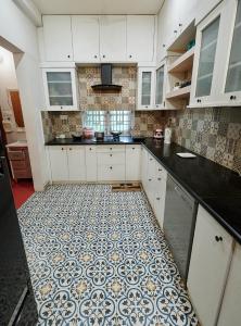 a kitchen with white cabinets and a tile floor at Zorba the Buddha in Begusarai