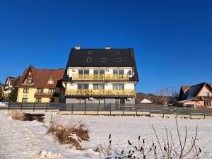 a building with a black roof in the snow at Apartament Kluskowe Widoki in Kluszkowce