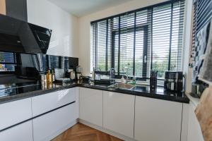 a kitchen with white cabinets and a large window at Dutch Design Villa with 6 luxurious bedrooms in Amsterdam