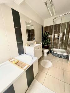 a bathroom with a sink and a tub and a toilet at Alpesi Apartman in Sopron