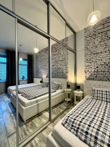 a bedroom with two beds and a brick wall at Royal City Centre Apartment in Poprad