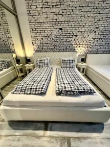two beds in a room with a brick wall at Royal City Centre Apartment in Poprad