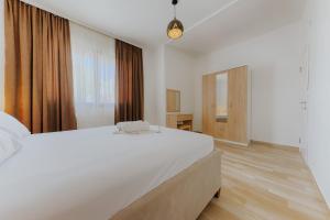 a white bedroom with a large bed and a window at Family Resort in Ulcinj
