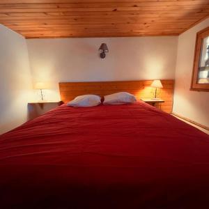 a bedroom with a large red bed with two pillows at LE NID ROUDELA in Garin