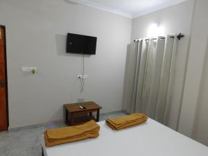 Ariel Guesthouse في باغا: غرفة نوم مع سرير وتلفزيون على الحائط