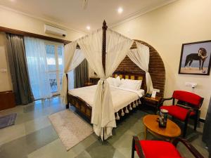 a bedroom with a canopy bed and a red chair at Dev Villa Resort in Rājsamand