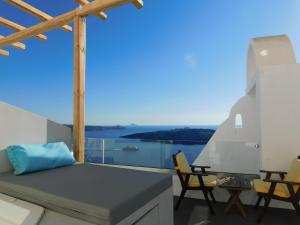 a balcony with a bed and chairs and a view of the ocean at Fira Caldera Suites in Fira