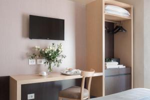 a hotel room with a desk with a tv on the wall at Hotel La Cisterna in San Gimignano