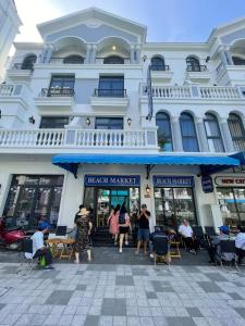 a large white building with people standing in front of a store at Beach Hotel Grand World (La La Homestay) in Phú Quốc