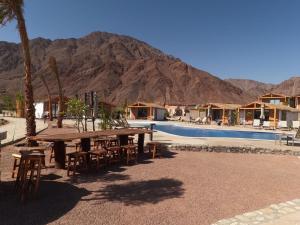 a picnic table and chairs next to a pool with a mountain at Ananda Beach Camp in Nuweiba