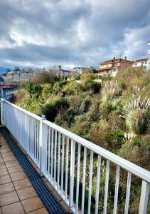 um corrimão branco num passadiço perto de uma colina com casas em Apartamento con terraza (Morriña) em Sada