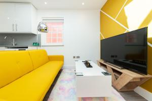 een woonkamer met een gele bank en een flatscreen-tv bij Well Equipped Apartment Guaranteed Weekly & Monthly Savings in Reading