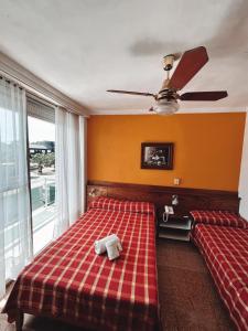 um quarto com uma cama de xadrez vermelho e uma ventoinha de tecto em HOTEL MILESI NECOCHEA em Necochea
