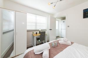 a white bedroom with a desk and a bed at Well Equipped Apartment Guaranteed Weekly & Monthly Savings in Reading