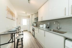 a kitchen with white cabinets and bar stools at Well Equipped Apartment Guaranteed Weekly & Monthly Savings in Reading