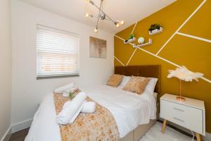 een slaapkamer met 2 bedden en een muur met gele accenten bij Well Equipped Apartment Guaranteed Weekly & Monthly Savings in Reading