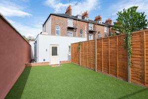 a backyard with a wooden fence and green grass at Well Equipped Apartment Guaranteed Weekly & Monthly Savings in Reading