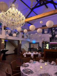 uma sala de jantar com mesas brancas e um lustre em B & B M 3 em Merkelbeek