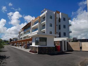 een wit gebouw met een parkeerplaats ervoor bij Paille en Queue apartment in Grand Baie