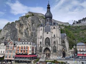 a large church with a mountain in the background at Le Patenier in Dinant