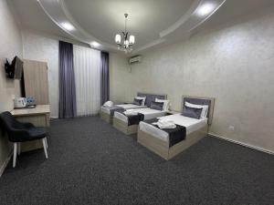 una habitación de hotel con 2 camas y una silla en Art Tashkent Hotel, en Tashkent