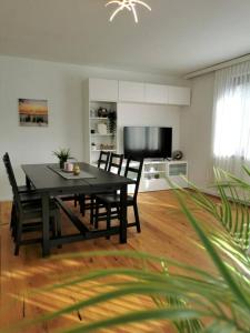 a dining room with a black table and chairs at Wörthersee: Gemütliche Wohnung in Klagenfurt