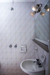 La salle de bains blanche est pourvue d'un lavabo et d'un miroir. dans l'établissement HOTEL MILESI NECOCHEA, à Necochea