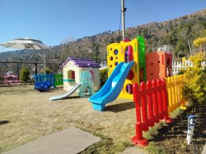 een speeltuin met kleurrijke speeltoestellen in een veld bij Kaffberry Cafe & Homestays in Kūd