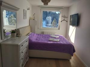 a bedroom with a purple bed and a window at OLIMPIJSKA KUCA-Planinska Avantura in Jahorina