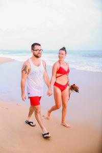 un hombre y una mujer caminando por la playa en Beach Lagoon Guesthouse, en Tangalle