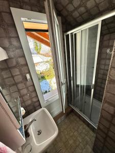 a bathroom with a sink and a shower with a window at Burgheim Siesta in Oberhofen am Thunersee