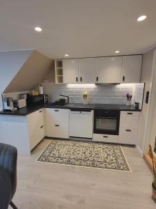 a kitchen with white cabinets and a rug at Slattum terrasse in Skytta
