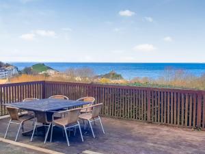 a table and chairs on a deck with a view of the ocean at Houndsfield in Ilfracombe