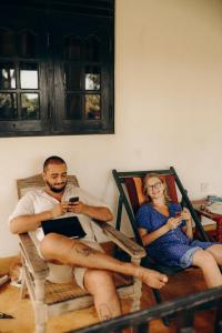 un hombre y una mujer sentados en sillas mirando sus celulares en Beach Lagoon Guesthouse, en Tangalle