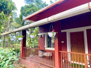 a red house with a balcony with a door at Coorg klusters estate stay in Virajpet