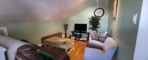 ein Wohnzimmer mit einem Sofa, Stühlen und einer Uhr in der Unterkunft Appartement Maufils in Québec