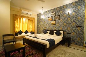 1 dormitorio con cama, silla y espejo en Hotel Vasshifa Palace, en Jaisalmer