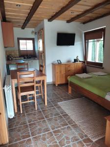 a bedroom with a bed and a table and a kitchen at Domek nad Krutynią in Piecki